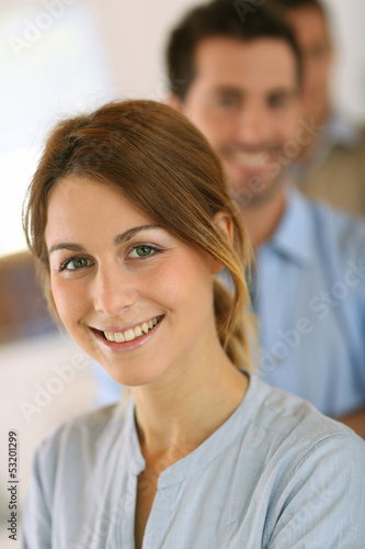 Photo: Cheerful young girl standing in front of business team Cheerful young girl standing in front of business team