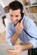 Cheerful man in office answering the phone