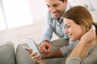 Photo: Young couple using smartphone at home Young couple using smartphone at home