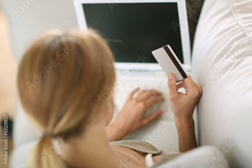 Photo: Back view of woman in sofa shopping on internet Back view of woman in sofa shopping on internet