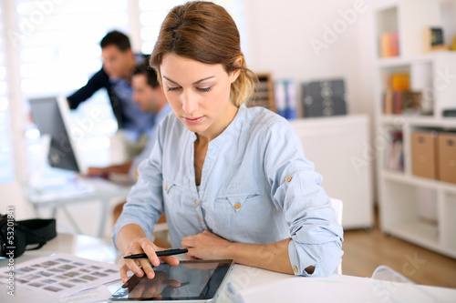 Photo: Girl in office working on digital tablet Girl in office working on digital tablet