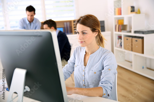 Photo: Young woman in office working on desktop Young woman in office working on desktop