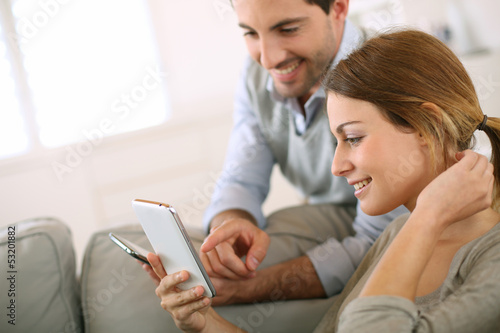 Photo: Young couple using smartphone at home Young couple using smartphone at home