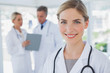 Smiling blonde haired doctor standing in her office