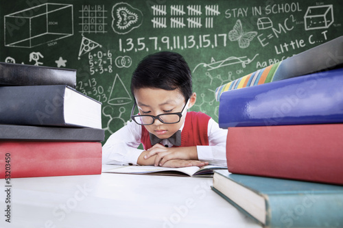 Photo: Close-up boy student reading books in class Close-up boy student reading books in class