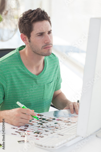 Photo: Photo editor working on computer and a contact sheet Photo editor working on computer and a contact sheet