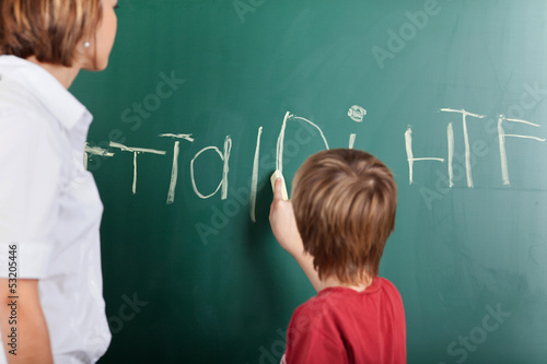 Photo: Young boy writing on the blackboard Young boy writing on the blackboard