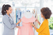 Photo: Attractive fashion designers adjusting a dress Attractive fashion designers adjusting a dress