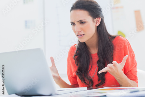 Photo: Annoyed designer gesturing in front of her laptop Annoyed designer gesturing in front of her laptop