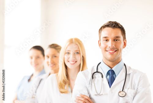 Photo: male doctor in front of medical group male doctor in front of medical group