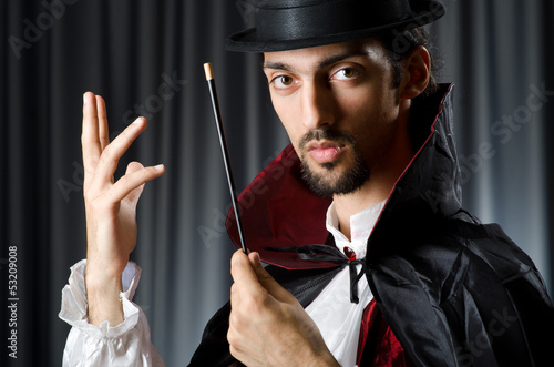Photo: Magician in the dark room with wand Magician in the dark room with wand