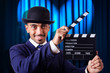 Man with movie clapper on curtain background