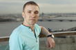 A young man in a turquoise shirt, short sleeve.