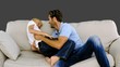 Father tickling son on the sofa on grey background