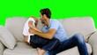 Father tickling son on the sofa on green screen