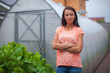 Young woman standing near her greenhouse