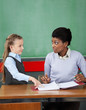 Foto: Schoolgirl Pointing In Binder While Teacher Looking At Her Schoolgirl Pointing In Binder While Teacher Looking At Her