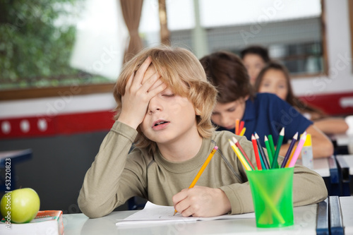 Photo: Tired Schoolboy Sitting At Desk In Classroom Tired Schoolboy Sitting At Desk In Classroom