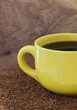 Yellow mug with coffee on the table with a instant coffee granul