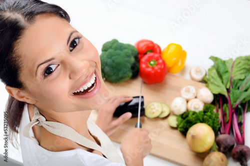 Photo: Smiling woman in the kitchen chopping vegetables Smiling woman in the kitchen chopping vegetables