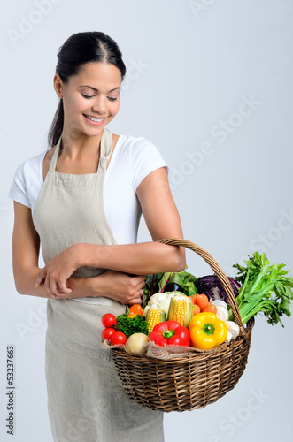 Photo: Woman with raw fresh produce ingredients in a basket Woman with raw fresh produce ingredients in a basket