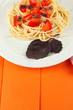 Spaghetti with tomatoes and basil leaves on wooden background