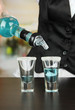Barmen hand with bottle  pouring beverage into glasses,