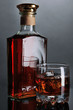 Photo: Brandy glass with ice and bottle on grey background Brandy glass with ice and bottle on grey background