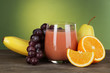 Glass of fresh juice on table on green background