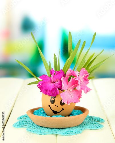 Photo: Flowers growing from egg shell, on bright background Flowers growing from egg shell, on bright background