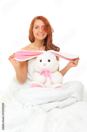 Photo: young woman in bed with a plush hare young woman in bed with a plush hare