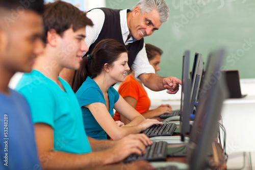 Photo: middle aged teacher teaching computer to students middle aged teacher teaching computer to students