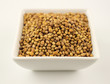 Macro of coriander seeds in a bowl isolated on white