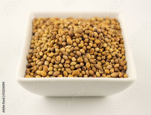 Photo: Macro of coriander seeds in a bowl isolated on white Macro of coriander seeds in a bowl isolated on white