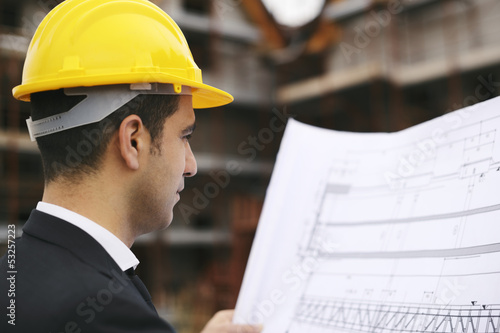 Photo: Architect in construction site looking at building plans Architect in construction site looking at building plans