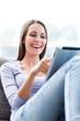 Woman using digital tablet on sofa