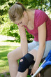 Junge Frau legt Kniebandage an