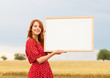 Redhead girl with blackboard at wheat field