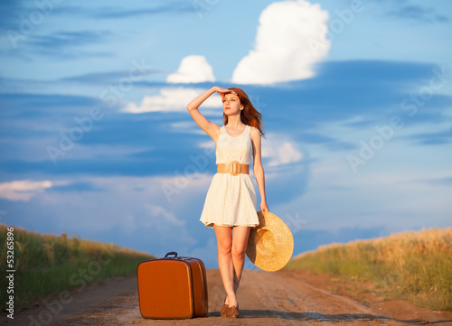 Photo: Redhead girl with suitcase at outdoor. Redhead girl with suitcase at outdoor.