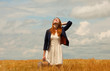 Redhead girl with suitcase at spring wheat field.