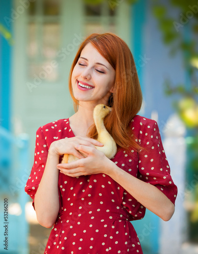 Photo: Redhead girl with duck near old house Redhead girl with duck near old house