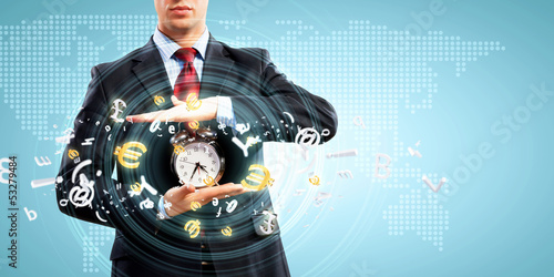 Photo: Business man holding alarmclock Business man holding alarmclock