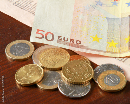 Photo: Money: euro coins and bills close up isolated on wood background Money: euro coins and bills close up isolated on wood background