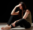 Depressed woman sitting on floor isolated on black background
