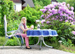 Frau sitzt am Tisch auf der Terrasse