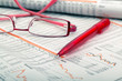 a ballpoint pen and reading glasses on a newspaper