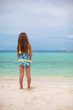 Beautiful little girl alone looks at the sea on the white beach