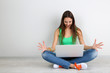 Photo: Beautiful young woman sitting with laptop in room Beautiful young woman sitting with laptop in room
