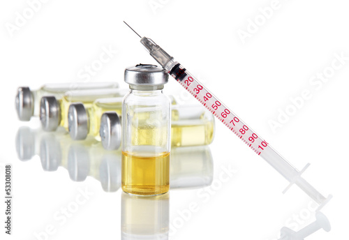 Photo: Medical bottles and syringe on light gray background Medical bottles and syringe on light gray background