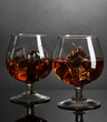 Brandy glasses with ice on grey background
